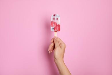 Photo of Woman holding berry popsicle on pink background, closeup