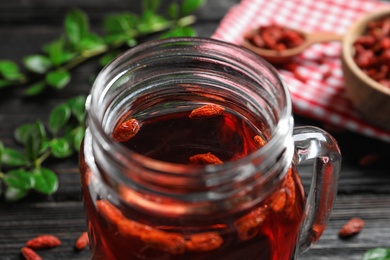 Photo of Healthy goji juice in mason jar on wooden table, closeup