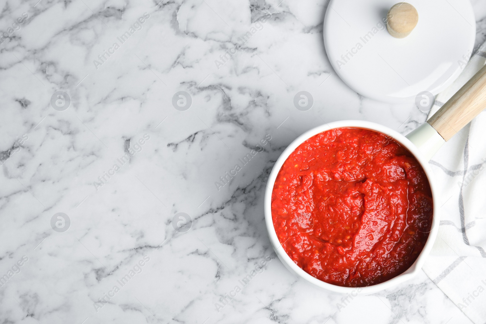 Photo of Delicious tomato sauce in pan on marble table, top view. Space for text