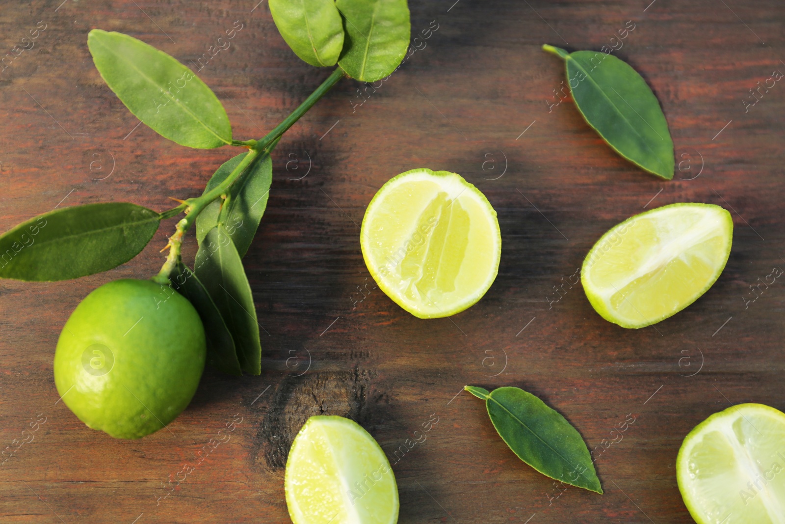 Photo of Fresh limes and leaves on wooden table, flat lay