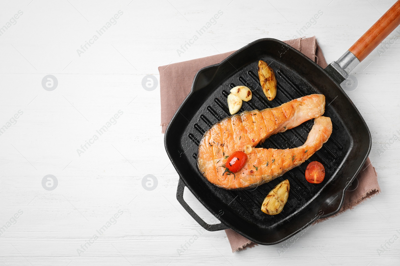 Photo of Frying pan with tasty salmon steak on wooden background