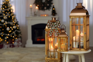 Photo of Christmas lanterns with burning candles in decorated living room. Space for text