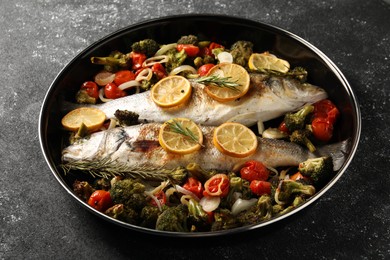 Photo of Baked fish with vegetables, rosemary and lemon on black textured table