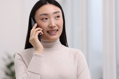 Photo of Portrait of smiling businesswoman talking on smartphone in office