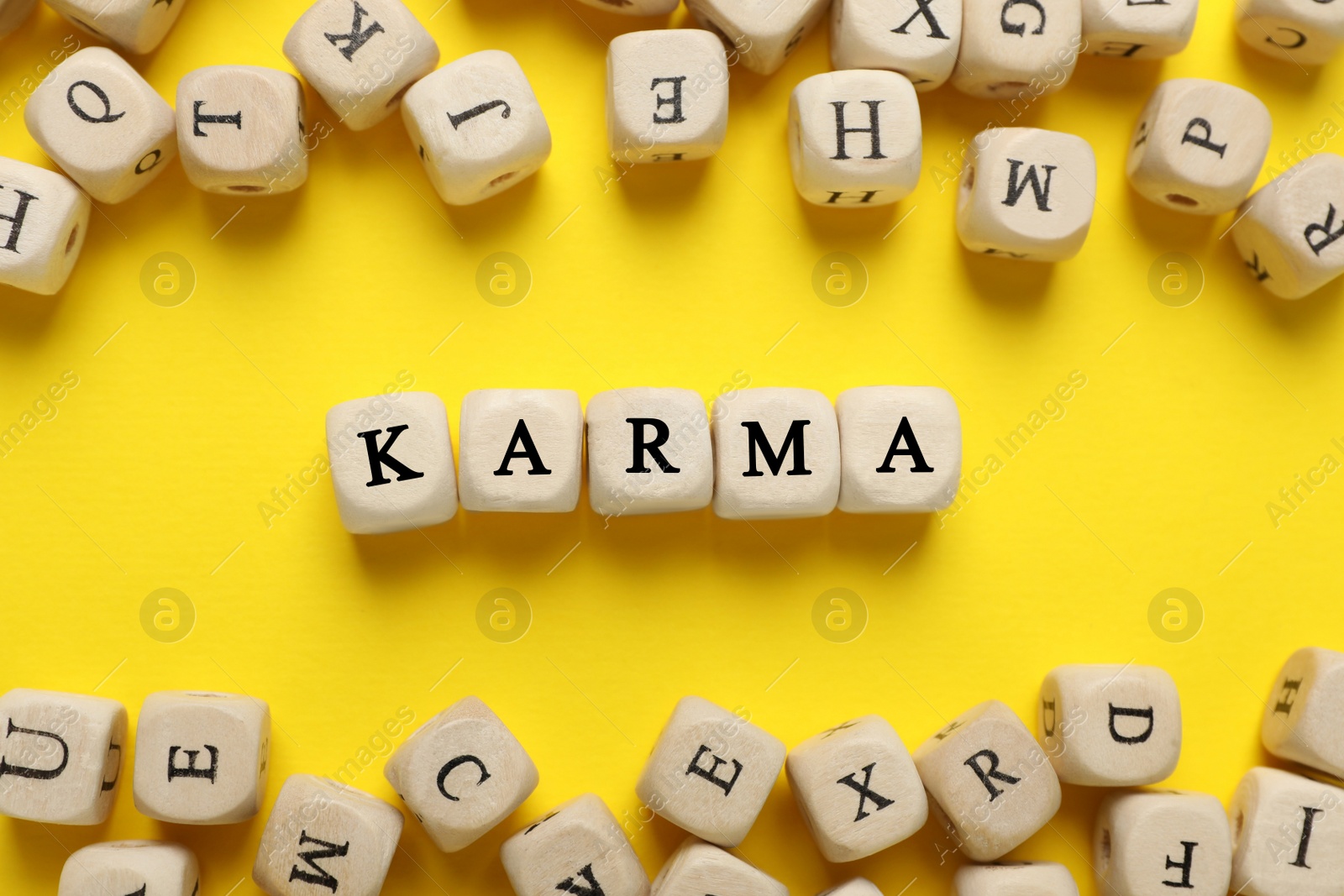 Photo of Word Karma made of cubes with letters on yellow background, flat lay