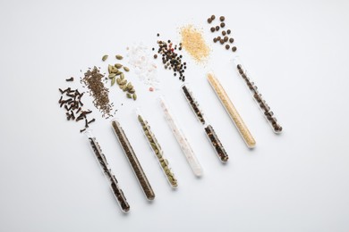 Photo of Test tubes with various spices on white background, flat lay