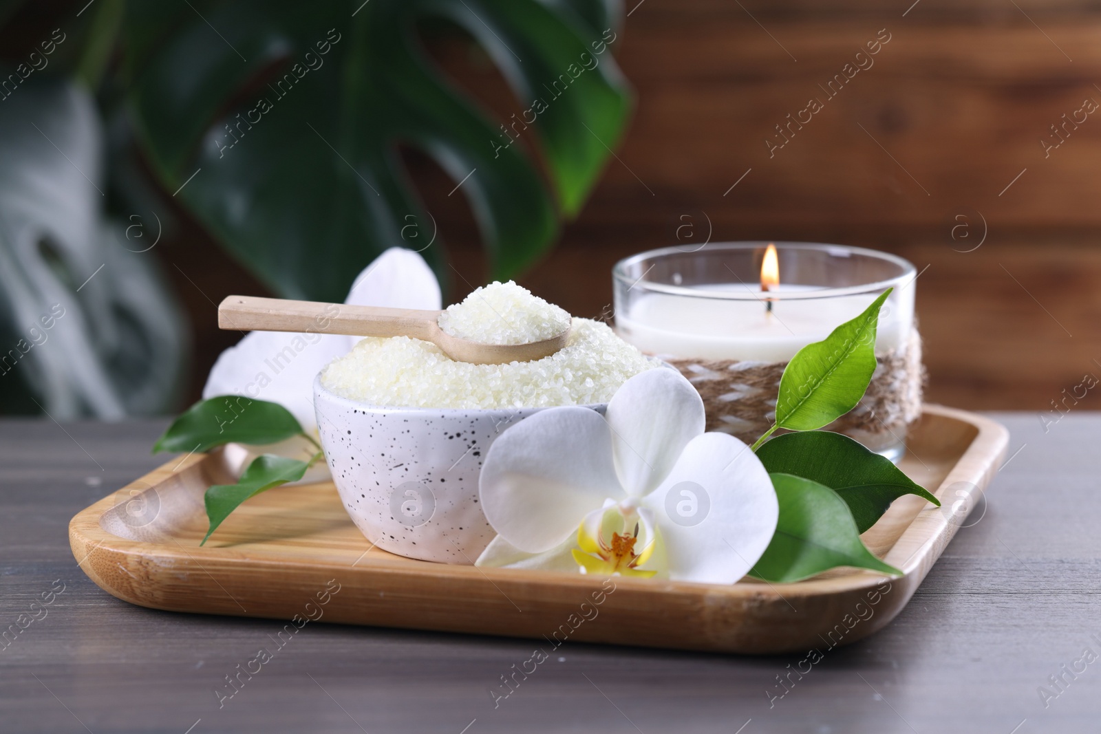 Photo of Natural sea salt in bowl, candle and beautiful orchid flower on wooden table