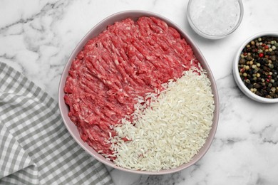 Photo of Bowl of forcemeat with rice and spices for preparing stuffed cabbage rolls on white marble table, flat lay