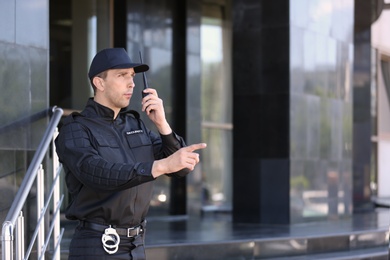 Male security guard using portable radio transmitter outdoors