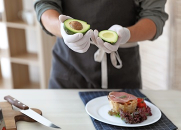 Photo of Professional chef preparing dish on table in kitchen, closeup