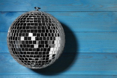 Photo of Shiny disco ball on blue wooden background, top view. Space for text