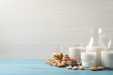 Different nut milks on light blue wooden table. Space for text