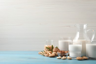 Photo of Different nut milks on light blue wooden table. Space for text