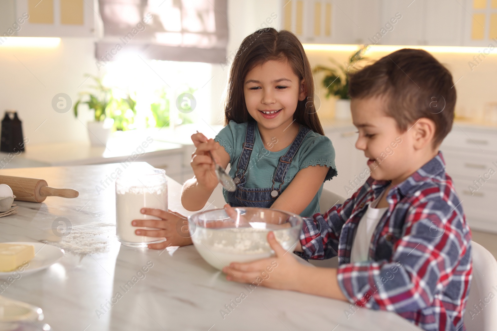 Photo of Cute little children cooking dough in kitchen at home