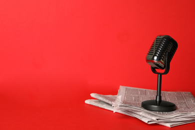 Photo of Newspapers and vintage microphone on red background, space for text. Journalist's work