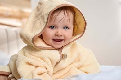 Photo of Cute little baby in yellow hooded towel on bed after bath