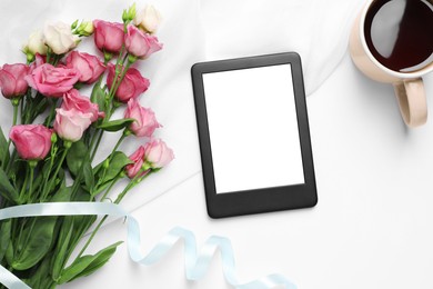 Photo of Modern e-book reader, flowers and cup of tea on white table, flat lay