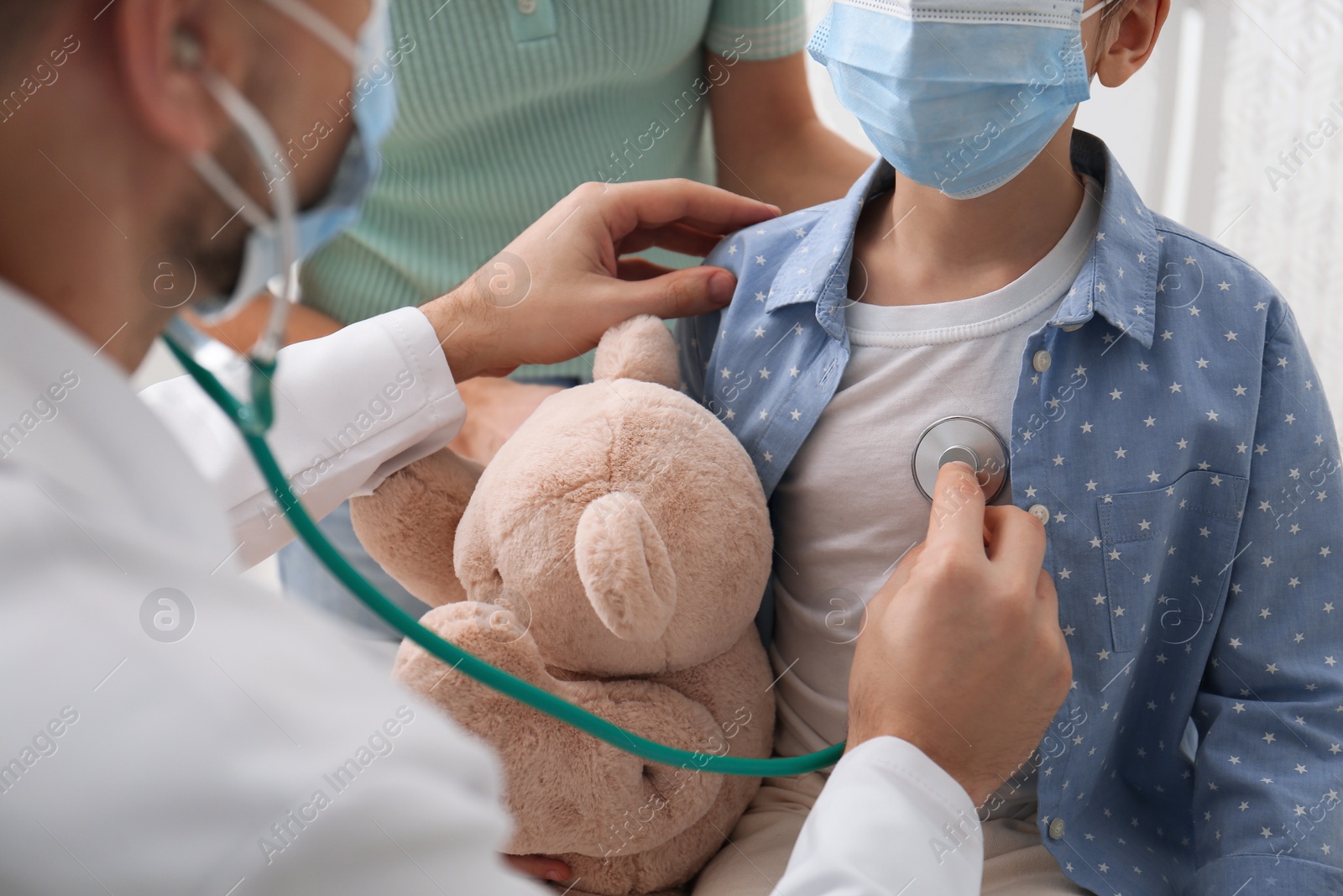 Photo of Pediatrician examining little girl in hospital. Wearing protective masks