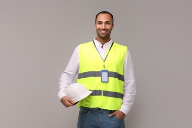 Engineer with hard hat and badge on grey background