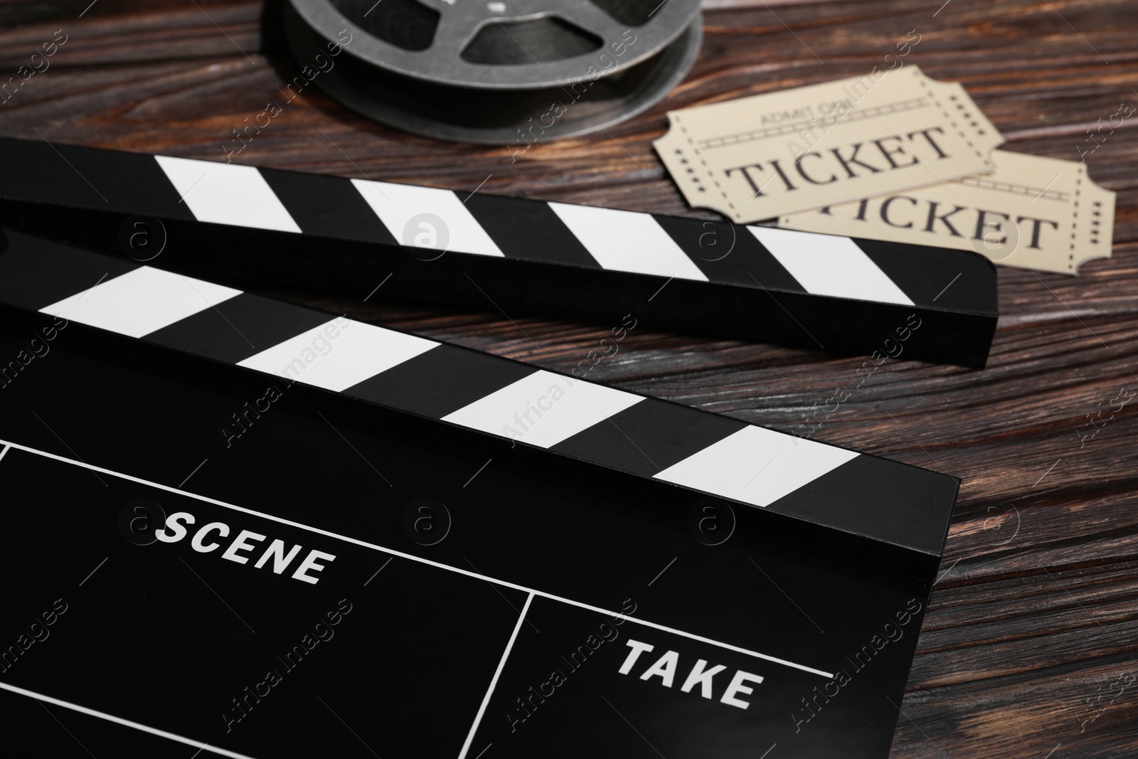 Photo of Clapperboard, movie tickets and film reel on wooden table, closeup