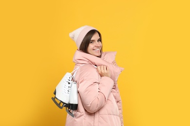 Photo of Happy woman with ice skates on yellow background