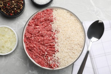 Minced meat with rice in bowl and other ingredients for stuffed cabbage rolls on light grey table, flat lay