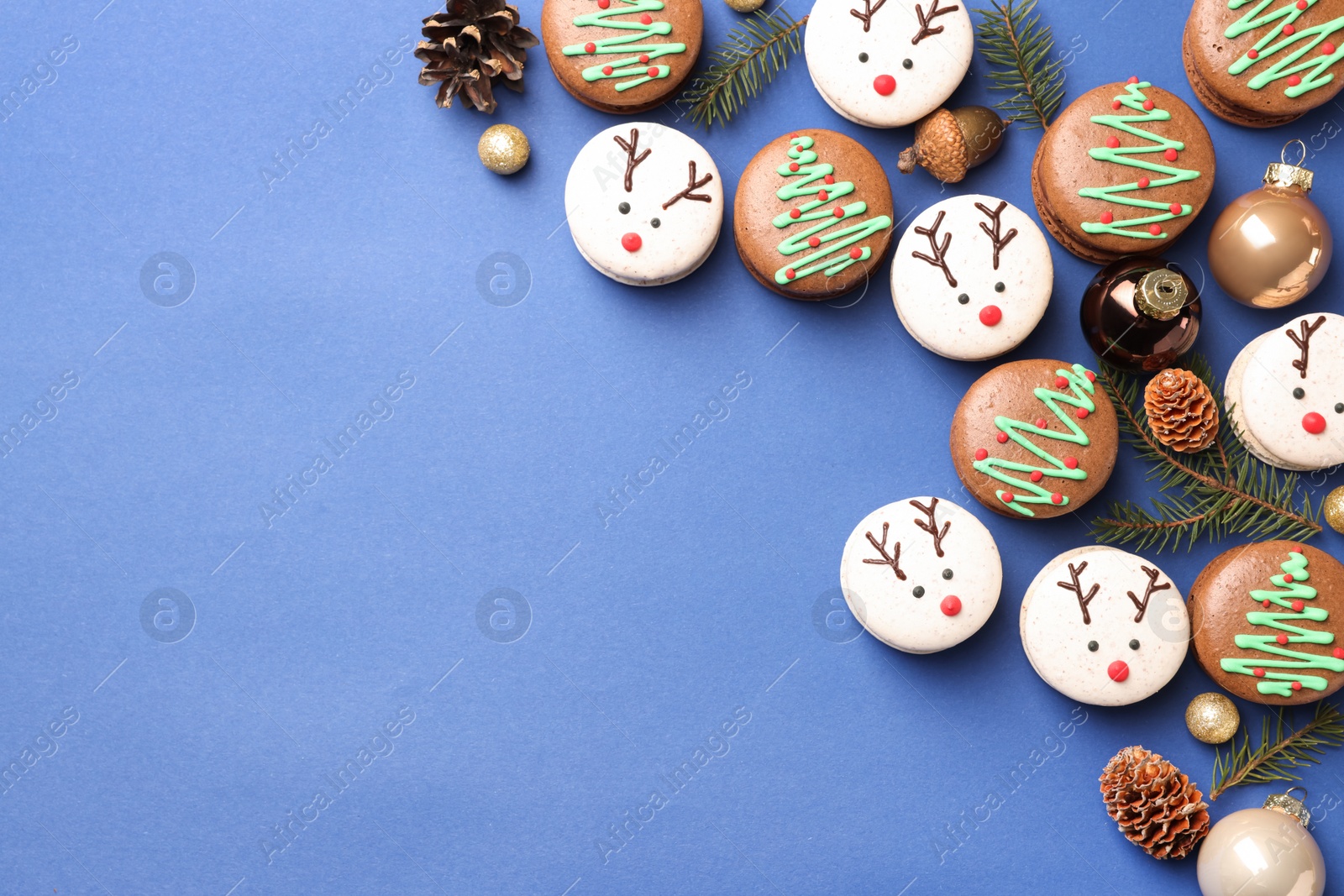 Photo of Beautifully decorated Christmas macarons on blue background, flat lay. Space for text