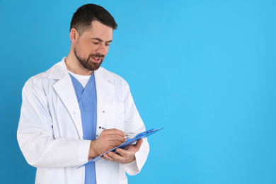 Photo of Portrait of mature doctor with clipboard against blue background, space for text