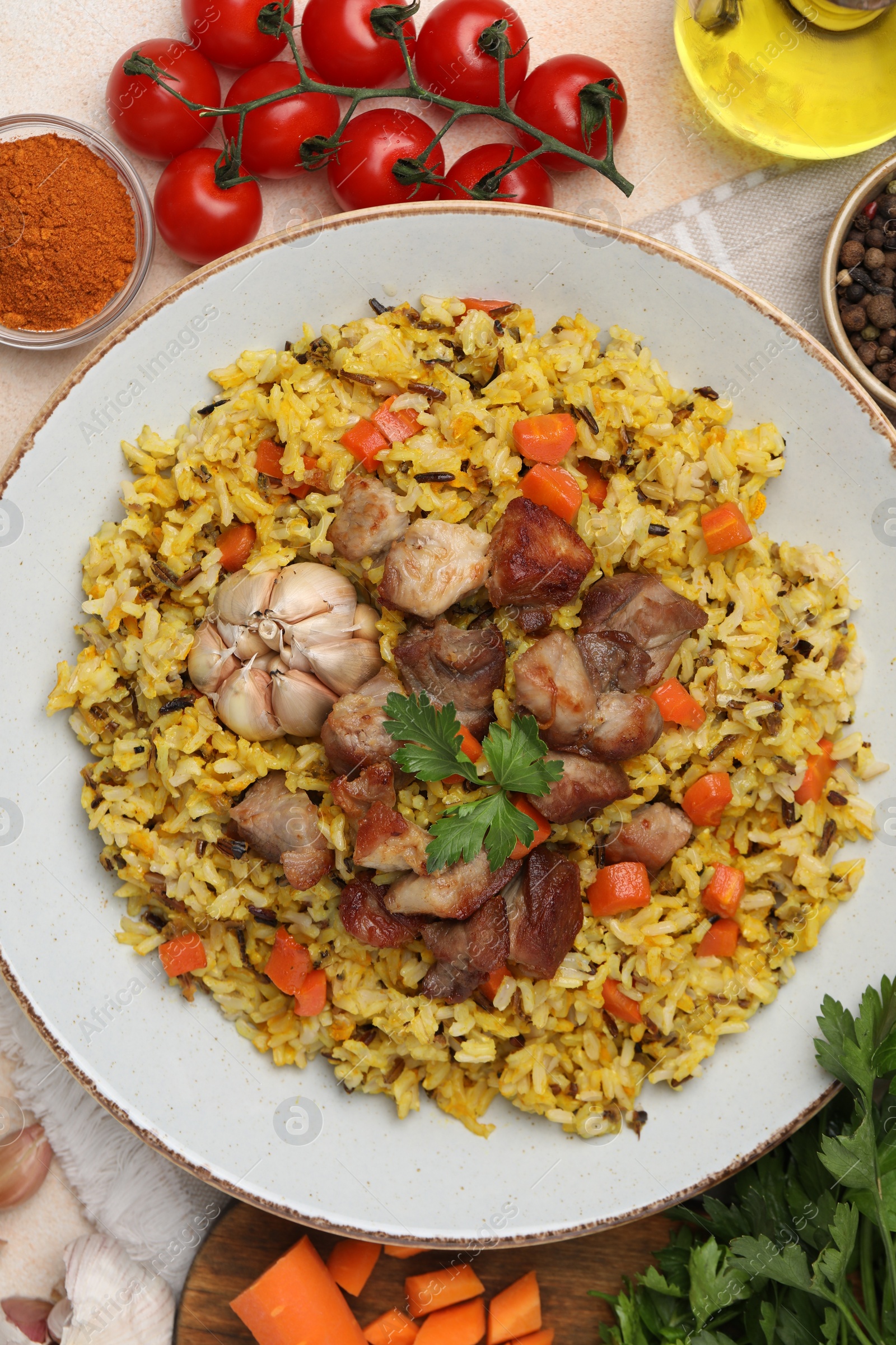 Photo of Delicious pilaf and products on beige table, flat lay