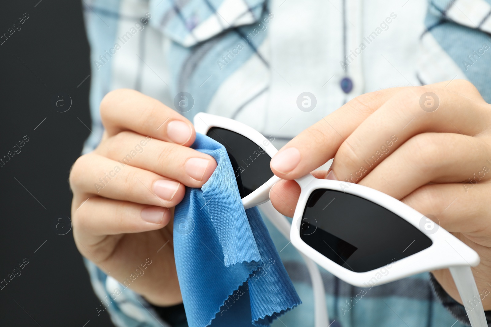 Photo of Woman wiping sunglasses with microfiber cleaning cloth, closeup