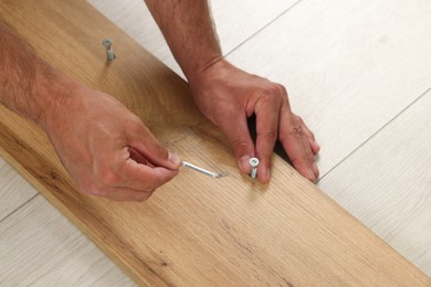 Man with hex key assembling furniture on floor, closeup