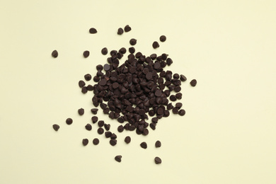 Photo of Pile of delicious chocolate chips on beige background, top view