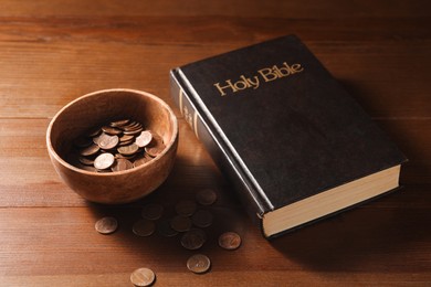 Donate and give concept. Coins in bowl and Bible on wooden table