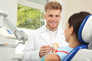 Photo of Professional dentist showing patient jaws model in clinic