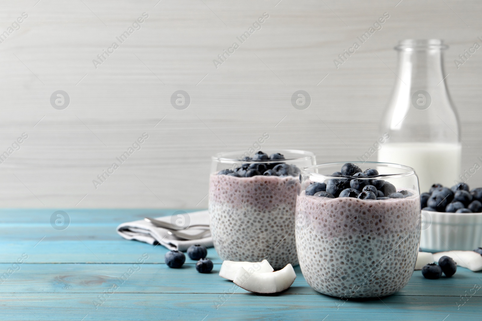Photo of Delicious chia pudding with blueberries on light blue wooden table, space for text