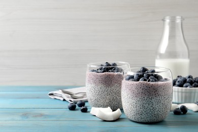 Photo of Delicious chia pudding with blueberries on light blue wooden table, space for text