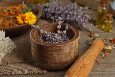 Photo of Mortar with pestle and dry lavender flowers on wooden table. Medicinal herbs
