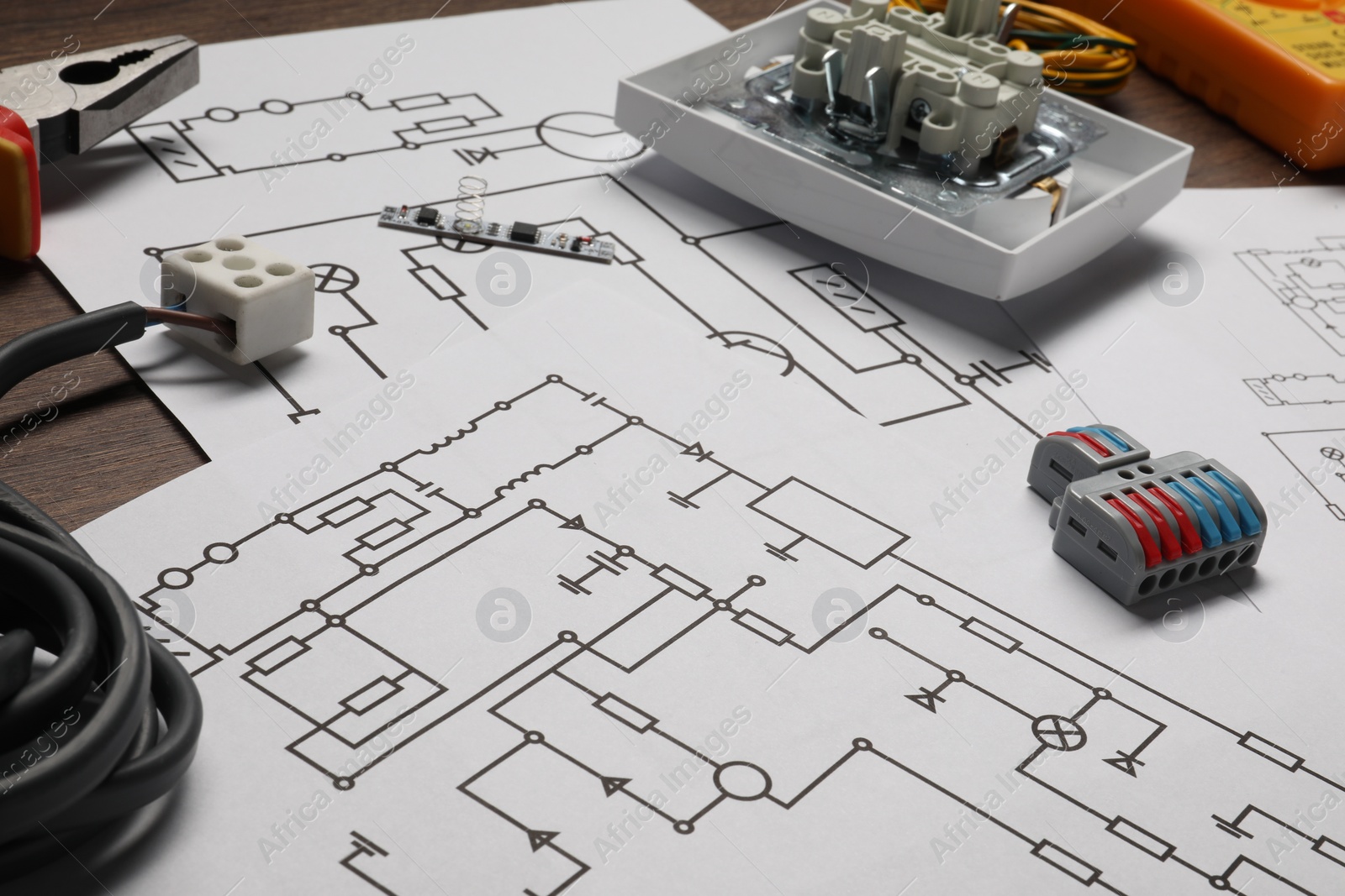 Photo of Wiring diagrams and different electrician's equipment on wooden table