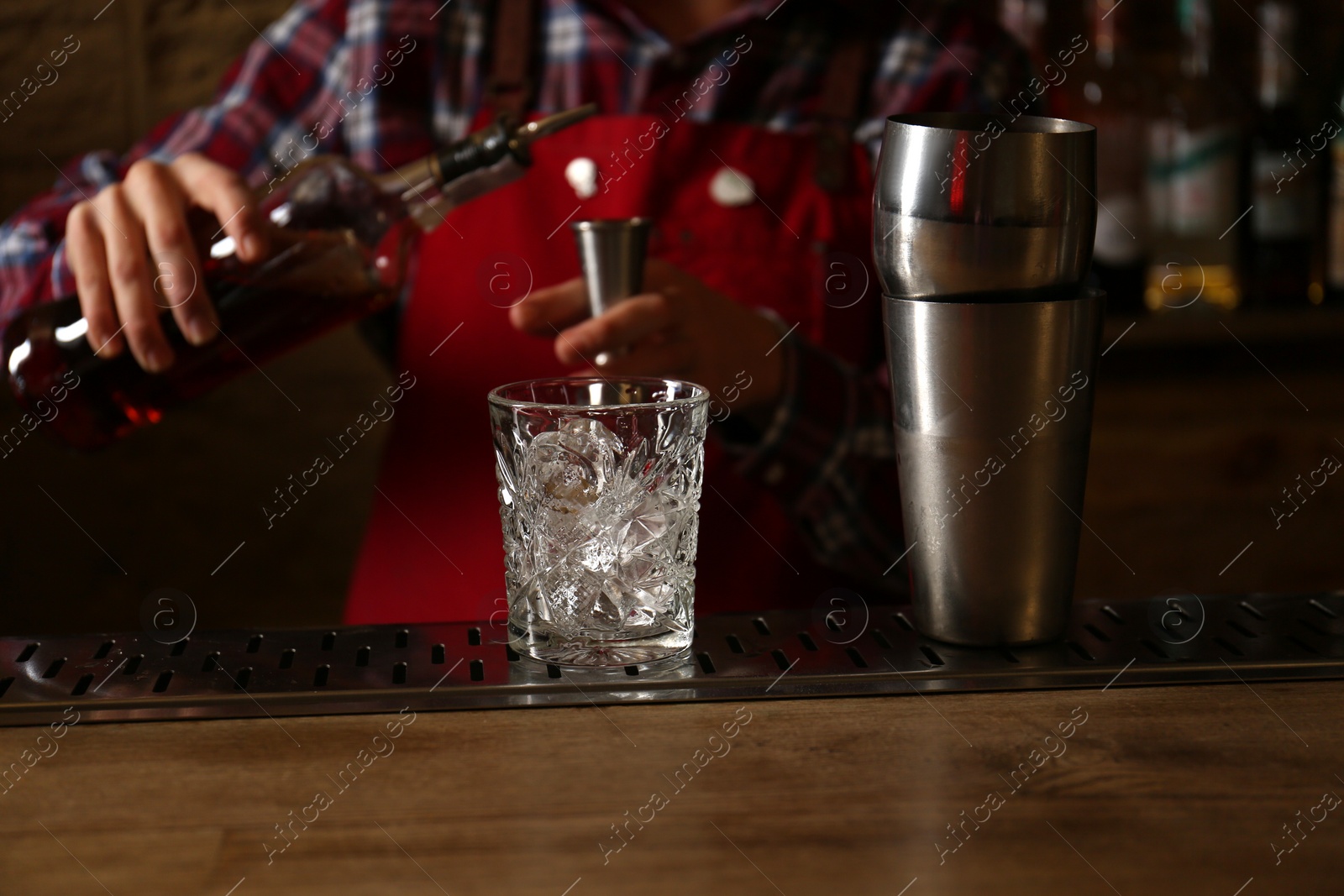 Photo of Bartender preparing fresh alcoholic cocktail at bar counter, focus on glass