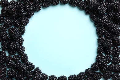 Frame of ripe blackberries on light blue background, flat lay. Space for text