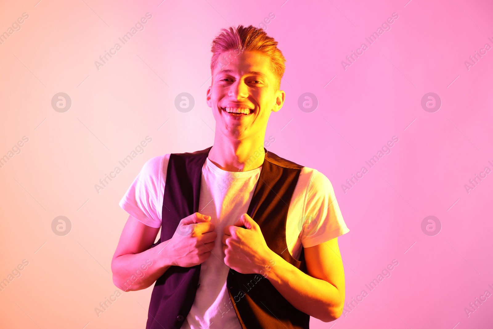 Photo of Stylish young man on pink background in neon lights