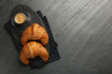 Delicious fresh croissants and cup of coffee on gray table, flat lay. Space for text