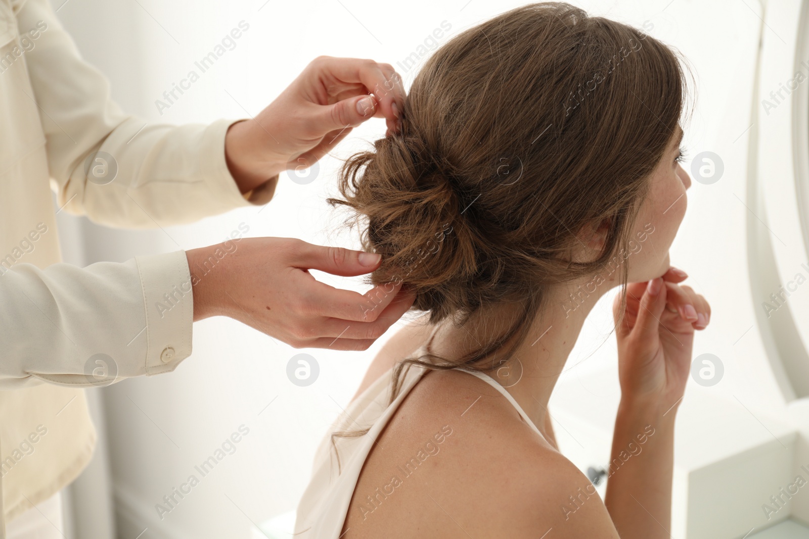 Photo of Hair stylist preparing bride for her wedding indoors