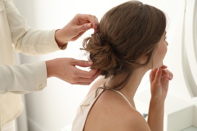 Photo of Hair stylist preparing bride for her wedding indoors