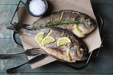 Photo of Delicious baked fish served on wooden rustic table, top view. Seafood