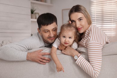 Photo of Family with little daughter spending time together on sofa at home
