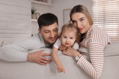 Family with little daughter spending time together on sofa at home