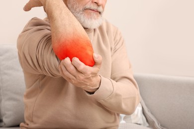 Man suffering from rheumatism in elbow at home, closeup