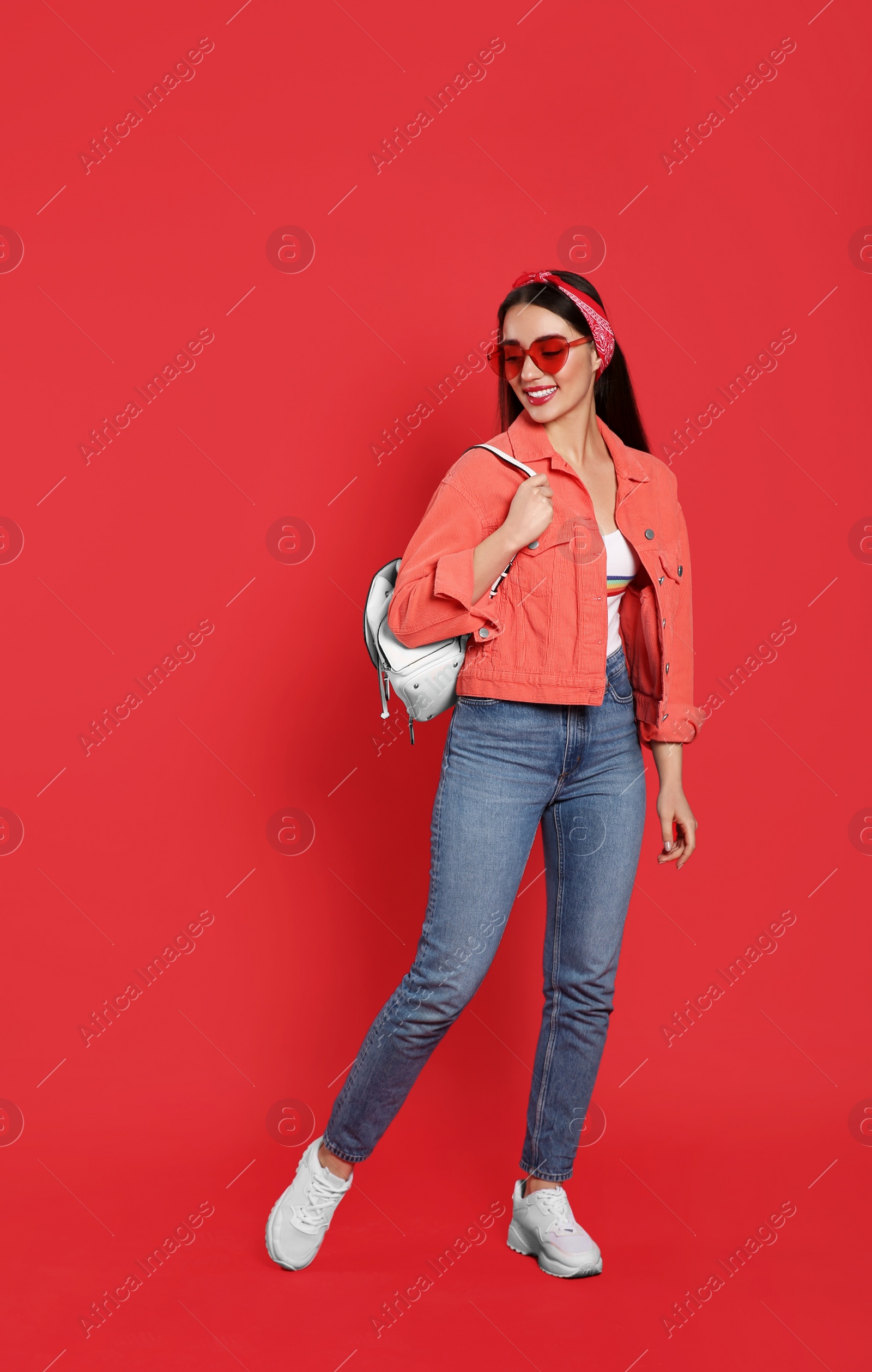 Photo of Beautiful young woman with stylish leather backpack on red background