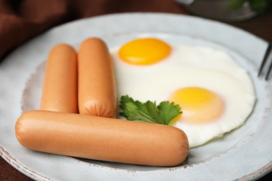 Photo of Delicious boiled sausages, fried eggs and parsley on table, closeup